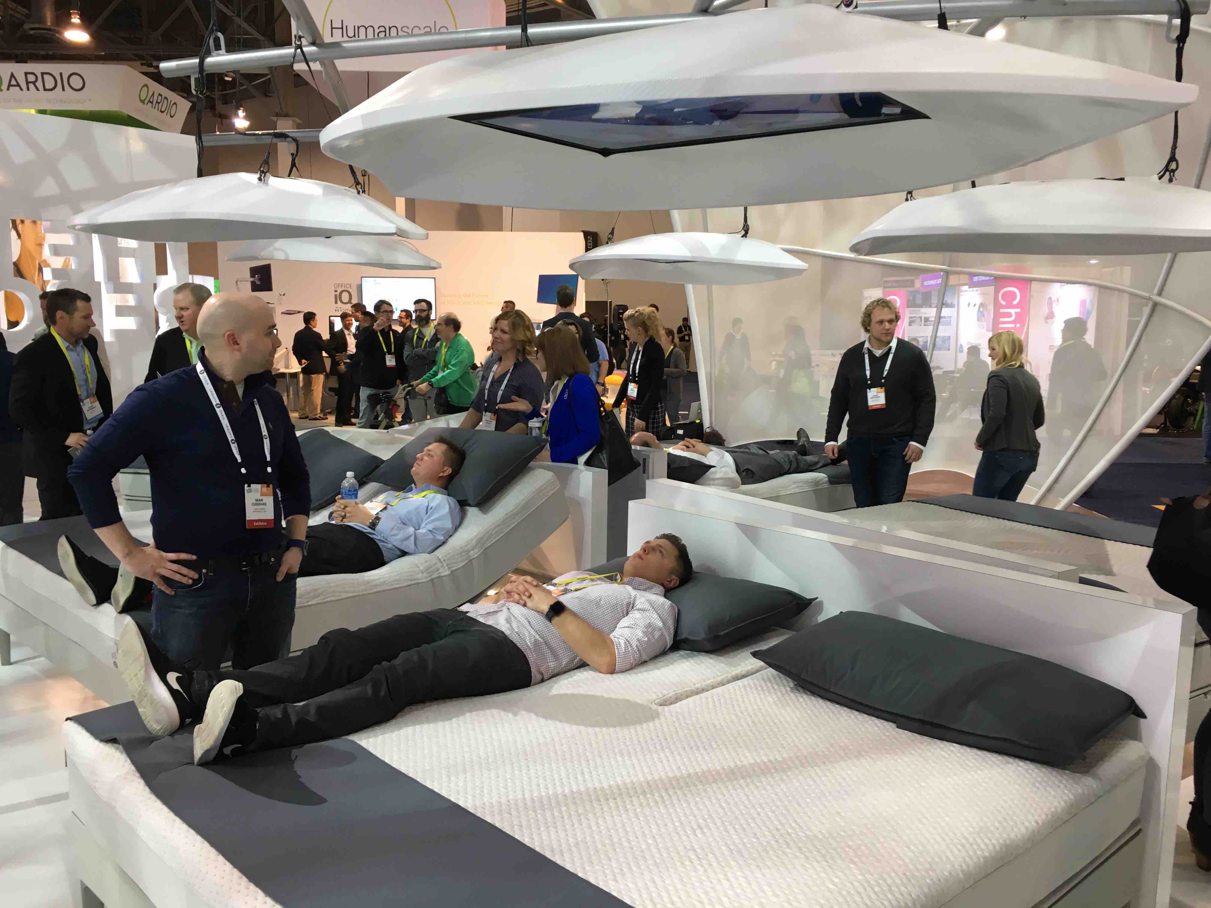 Man laying on white smart bed at a trade show
